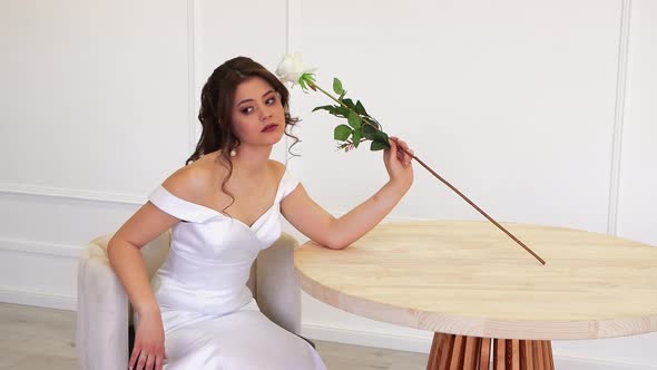 Beautiful Girl Sidiya at the Table Sniffing a White Rose Posing