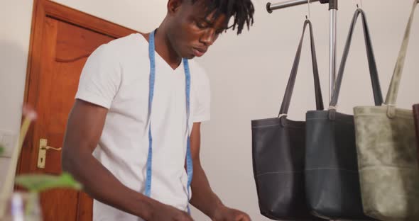 African american craftsman with dreadlocks arranging wallets and bags in leather workshop