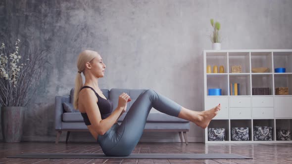 Young and sporty girl in sportswear is doing exercises in home interior.