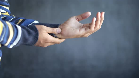 Man Suffering Pain in Hand Against Black Background