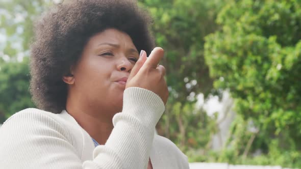 Video of plus size african american woman using inhalator outdoors