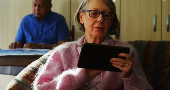 Senior woman using digital tablet in living room 4k