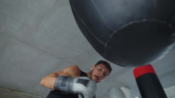 Low Angle View Male Boxer Training Aggressively with Boxing Bag