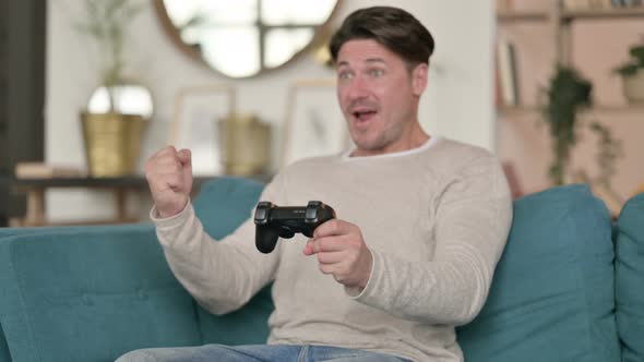 Successful Middle Aged Man Winning at Video Game at Home 