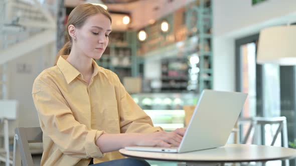 Professional Young Woman Using Laptop in Cafe