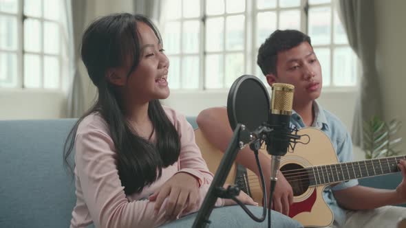 Asian Boy Playing Guitar And Girl Sing A Song At Home