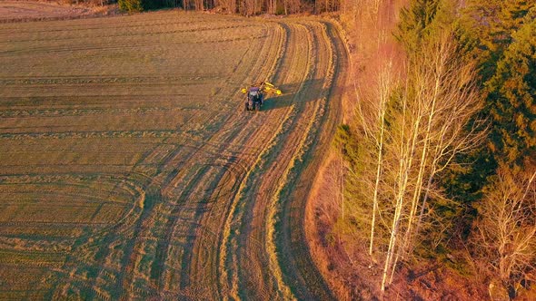 Aerial tracking drone shot, following a tractor plowing on a field, in the countryside of Soderhamn,