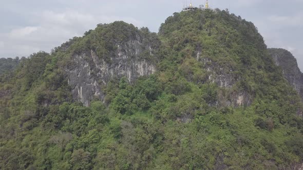 Aerial footage of Buddha on top of Tiger Cave Temple, Wat Thum Sua, stone rocks, Krabi, Thailand.