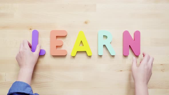 Word LEARN from multicolor wooden letters on wooden table.