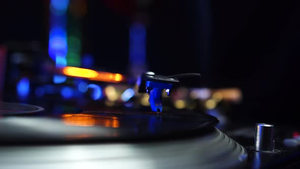 Needle of Professional DJ Gramophone on Vinyl Record Drink and Disco Lights