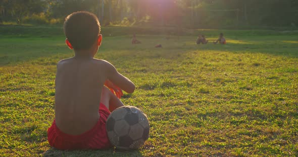 Sad Rural Boy Sitting With Old Ball alt
