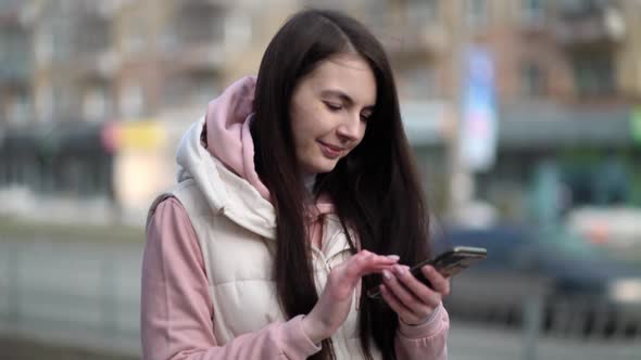 Happy Woman Typing By Mobile Phone Outdoors Walking in Urban Background