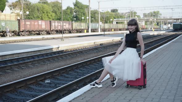 Pretty Coquette in Blackwhite Dress Poses on Suitcase at Railway