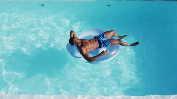 Mixed race man having fun sunbathing on inflatable in swimming pool