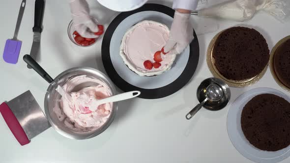 Chef Placing Sliced Strawberries on Layer of Cake That Already Has Some Cream on Top