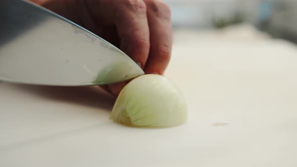 Close-up: Chef chopping an onion with fine pressure on a cutting surface in a professional kitchen