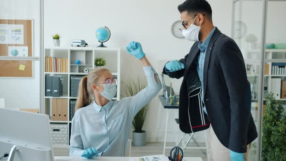 Office Workers Caucasian Girl and Arab Guy Doing Elbow High-five at Work During Quarantine