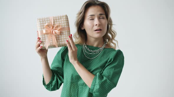 Slow Motion of Surprised Young Woman Shaking Decorated Gift Box and Smiling