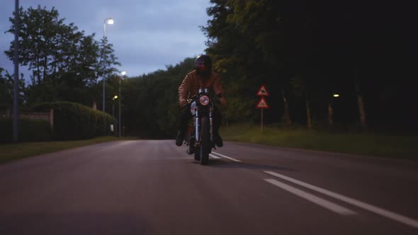Motorcycle Driven on a Concrete Road With the Backdrop of Street Lights alt