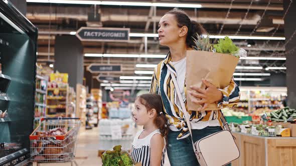 Portrait of Lovely Mom and Daughter in Supermarket with Packages Full of Greens and Fruits Healthy