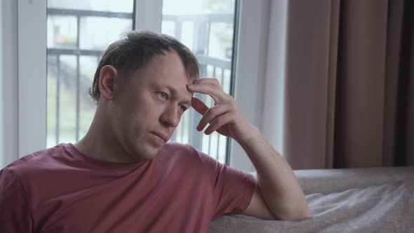 Portrait of Serious Man on Sofa Negative Emotions Window Background