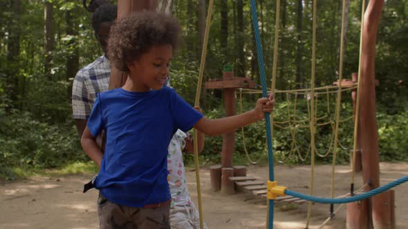 The child takes steps on the rope steps of the playground.