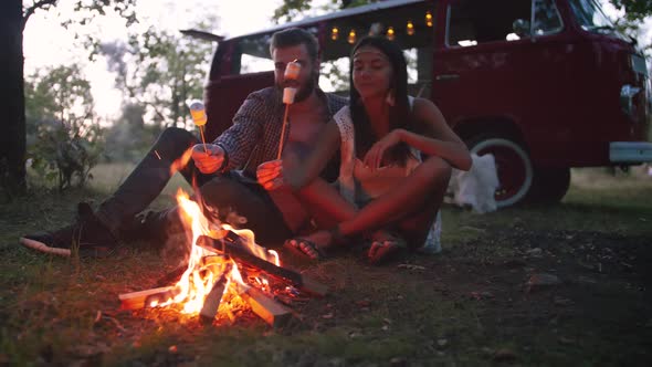 Beautiful Young Mixed Race Couple Roasting Marshmallows Over a Campfire While Enjoying Their Road