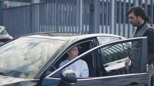 Elegant Man Opening Car Door for Beautiful Young Woman in Urban City Outdoors