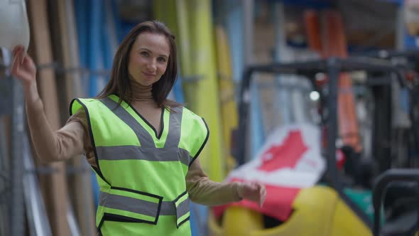 Young Canadian Warehouse Worker Taking Off Hard Hat Touching Hair Looking at Camera Smiling