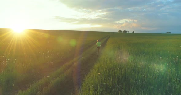 Sporty Child Runs Through a Green Wheat Field in Summer Rain. Evening Sport Training Exercises at