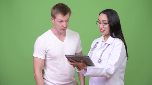 Young Asian Woman Doctor Giving Consultation To Young Man Patient