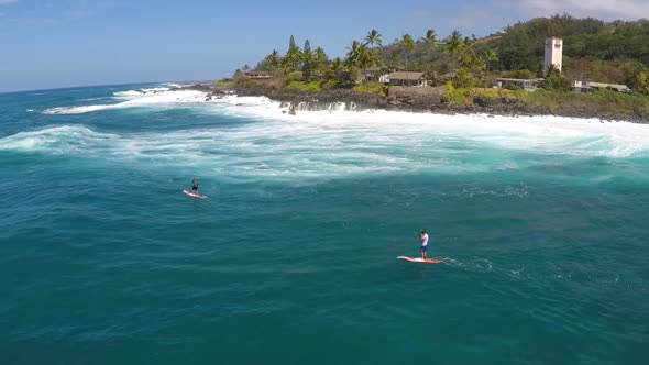 Aerial view of two men sup stand-up paddleboard surfing in Hawaii