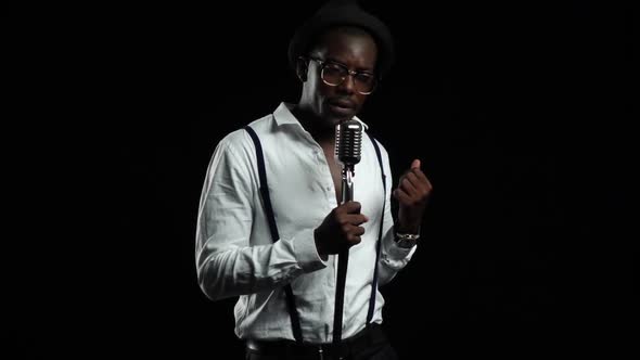 Singer Sings Into a Retro Microphone Spinning and Dancing Around Him. Black Background. Slow Motion