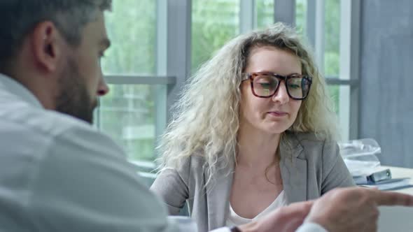 Businessman and Businesswoman Discussing Document on Tablet