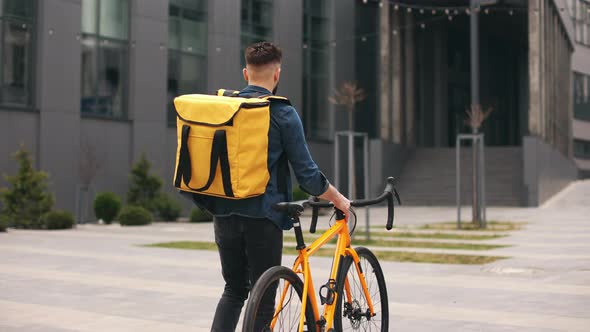 The Food Delivery Guy is Going and Looking at the Smartphone