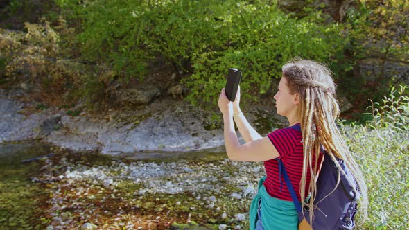 Girl Tourist with Backpack Takes Photo of Landscape