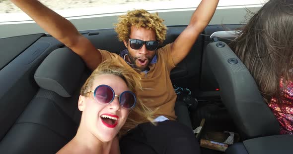 Handsome black man sticking his feet up of the convertible riding with friends