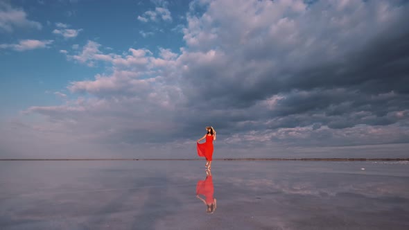 Portrait of a Young Woman in a Fluttering Dress. Girl Traveler Walks on a Pink Salt Lake