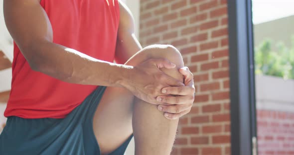 Fit african american man exercising at home and doing stretching at home