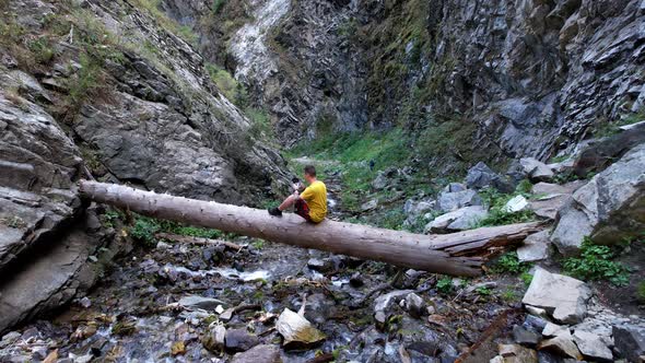 The Guy is Sitting on a Big Tree Above the River