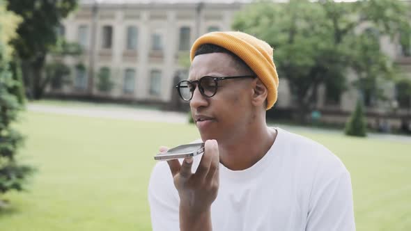 Happy Young Hipster is Sitting in the Park Talking Onthe Phone with a Smile Closeup Portrait