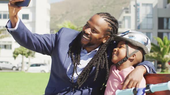 Video of happy african american father and son in helmet taking selfie outdoors