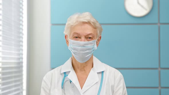 Cheerful mature lady doctor with grey hair in coat with stethoscope