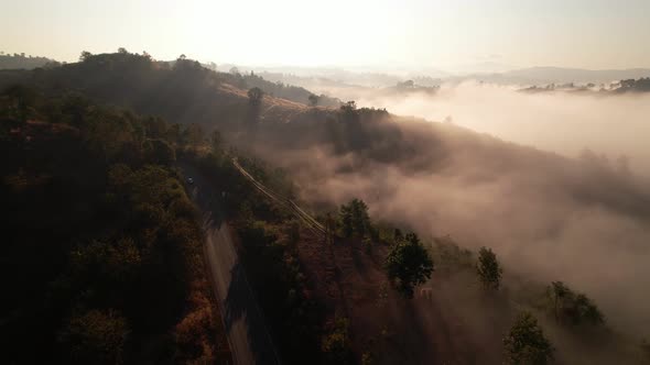 4K aerial view over mountain at sunrise in heavy fog. golden morning sunlight