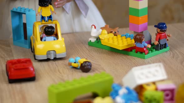 Little girl plays building blocks on a wooden table