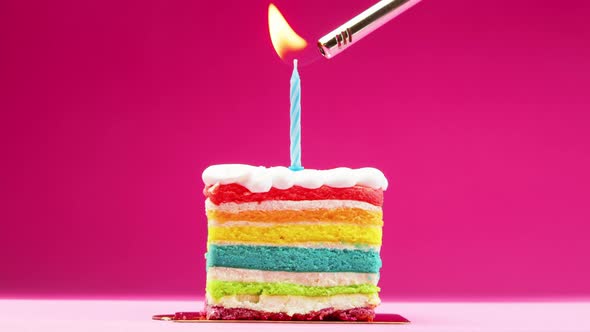 A Slice of Birthday Cake with a Bright Blue Candle on a Pastel Pink Background