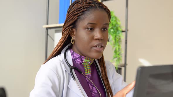 Young African American Woman Doctor with Headset Having Chat or Consultation on Laptop