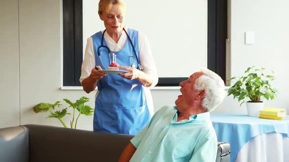 Nurse bringing cake for senior man birthday