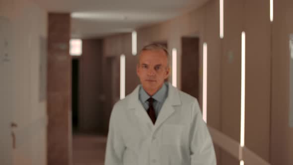 Confident Middle Aged Doctor Walking in Hospital Hallway