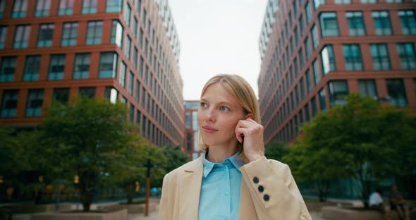 A Female Office Worker Talking on the Phone Through Wireless Headphones